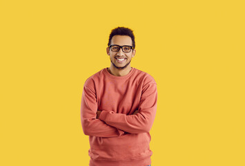 Studio portrait of happy male college or university student. Handsome young black man in glasses standing with his arms folded isolated on color background, smiling and looking at camera