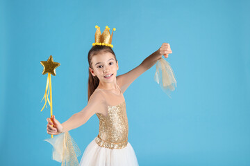 Cute girl in fairy dress with golden crown and magic wand on light blue background. Little princess © New Africa