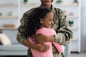 Closeup of african american girl hugging her dad soldier