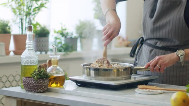 Person stirring hot veal shanks in frying pan