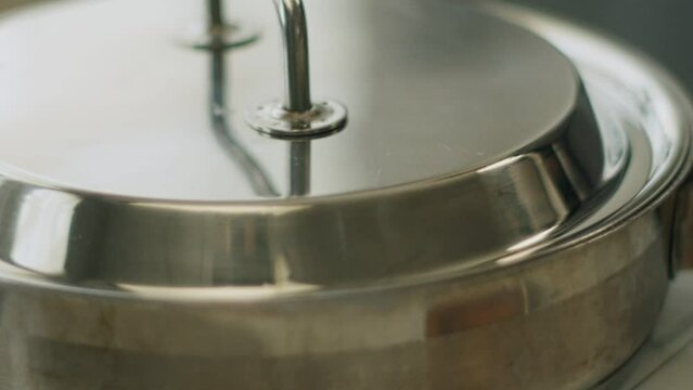 Woman cooking ossobuco and closing pan with lid