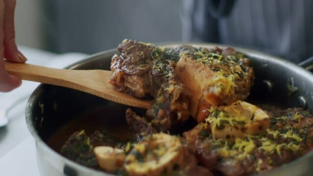 Woman serving delicious ossobuco on ceramic plate