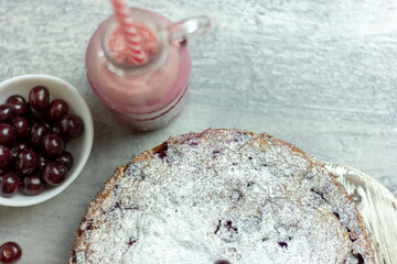 Homemade cherry pie and red cherry smoothie and sprinkled with berries on a gray table, close-up. Summer breakfast
