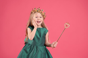 Obraz na płótnie Canvas Cute girl in fairy dress and golden crown holding magic wand on pink background. Little princess