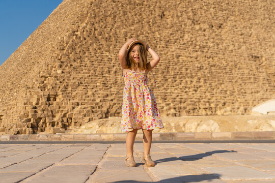 Cute little girl dancing in front of the Cheops pyramid on the Giza plateau.