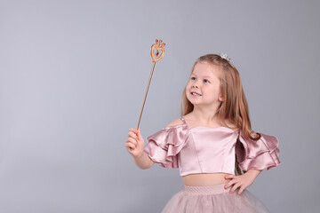 Cute girl in fairy dress with small crown and magic wand on light grey background, space for text. Little princess © New Africa