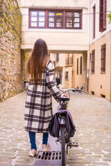 Fototapeta premium Pretty latin woman with sunglasses doing bicycle sightseeing in the city through the old town. Eco tourism in spring on vacation