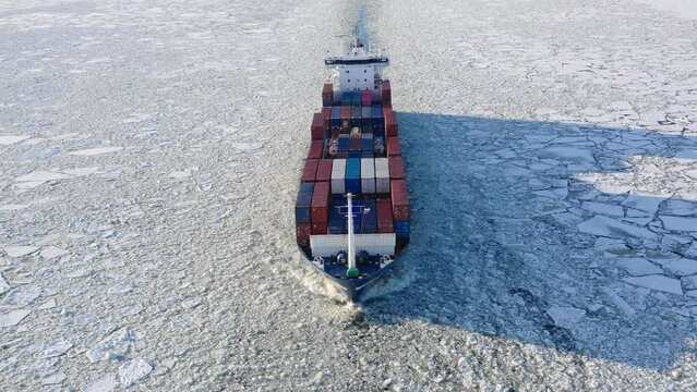 St. Petersburg, Russia, winter 2022: container ship goes through the ice floes, aerial view
