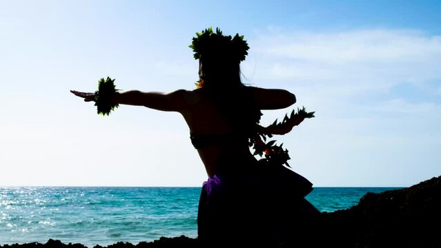 Beautiful woman silhouette performing hawaiian dancing at the beach