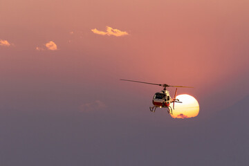 Naklejka na ściany i meble helicopter in flight at sunset in the high mountains