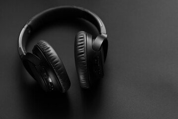 Fototapeta na wymiar Black wireless headphones on a black background