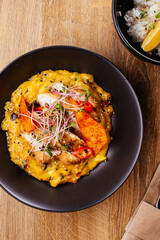 chicken curry with a black plate on a wooden background. restaur