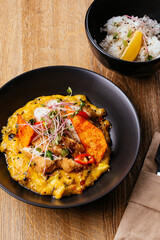 chicken curry with a black plate on a wooden background. restaur