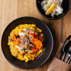 chicken curry with a black plate on a wooden background. restaur