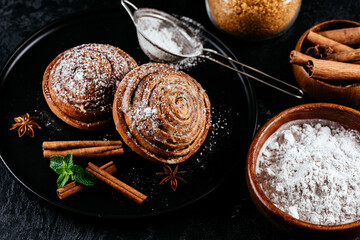 cinnamon buns on a dark background. coffee, sugar, berries