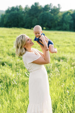 Mother Smiling At Her Baby Boy In Her Arms On A Summer Day