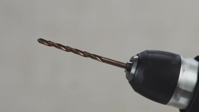 Closeup of spinning drill inserted into screwdriver. Drill bit inserted into perforator turns. Construction drilling tool