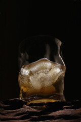 whiskey with ice in a curly glass on a dark background