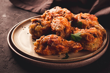Fried chicken legs, breaded, with spices and herbs, on a dark background, horizontal, no people, selective focus, toned.