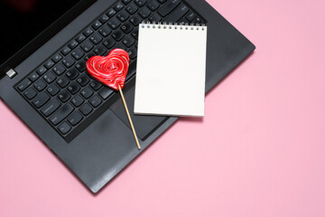 laptop, notepad, heart shaped lollipop on pink background. card, congratulations on Valentine's Day, Mother's Day. romantic background