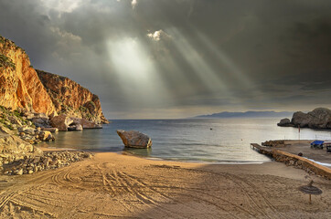  Pequeña  y solitaria cala de arena en Marruecos con un peñón de roca. Iluminada por un sol...