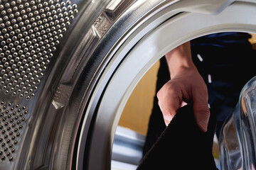 a man takes black clothes out of the washing machine after washing