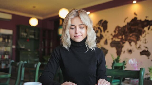 Beautiful girl finishing work on laptop, taking break in cafe, young woman working on computer, closing pc, drinking coffee and relax  sitting at table at cafe