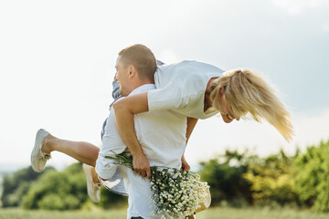 Summer Lifestyle concept. Young couple resting in field with wild flowers on summer day. Blond...