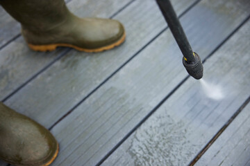 Close Up Of Man Jet Washing Patio Decking With Pressure Washer