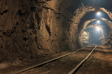 Fototapeta na wymiar Narrow gauge railroad in the underground mine horizon. Technologies of mining of minerals by the underground method. Underground mine for mining ore