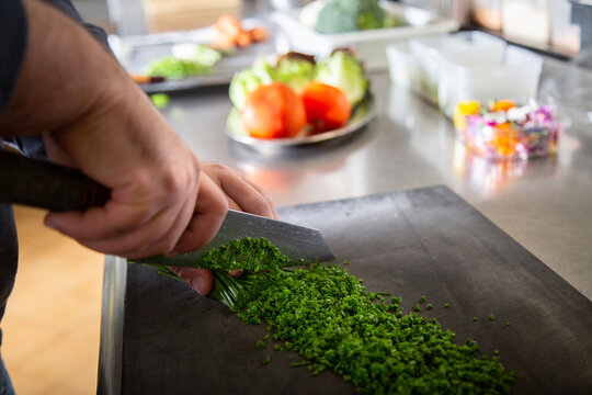 Unrecognizable cook chopping fresh herbs