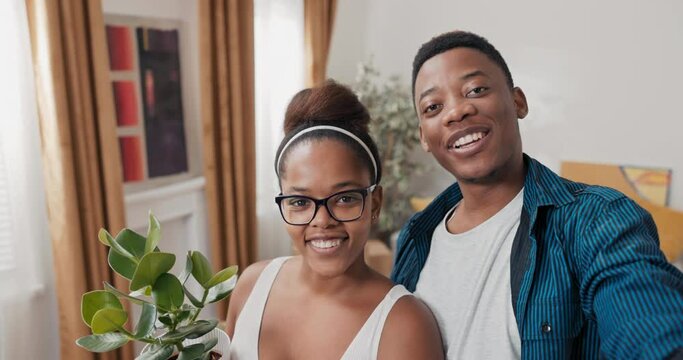The couple waves to the camera, smiles, shoots a video, vlogs for their parents, social media, internet, has webcam conversation with their friends, shows off the new apartment they moved into