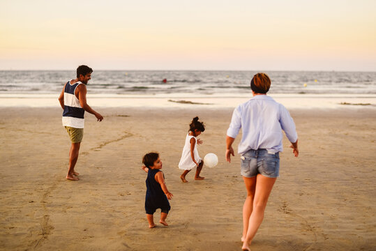 Cheerful diverse family playing with ball on beach