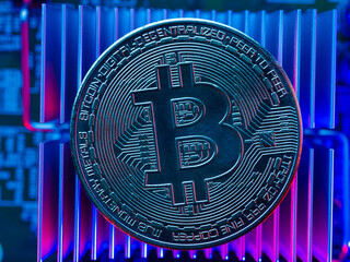 Cryptocurrency - bitcoin lies on the processor of a personal computer. Illuminated with blue neon light. Virtual reality, mining, cryptocurrency, crypto farm, virtual and real money, risk.