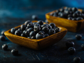 Blueberries in square bowls on a dark blue background. Close-up. Culinary - fresh juices, ingredient for meals, addition to breakfast cereals, dairy products. Medicine - vitamins, antioxidants.