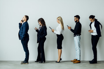 Businessmen on a line using their cellphones in queue