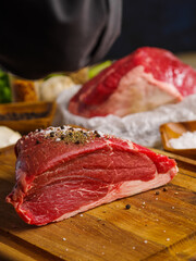 Large appetizing raw pieces of meat with spices on a wooden background. Macro shot. The concept is the preparation of products from meat - pork, veal, beef. Restaurant, hotel, advertising, banner.