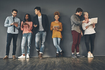 Fototapeta premium We take every opportunity to social network. Studio shot of a diverse group of creative employees social networking inside.