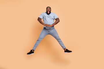 Fototapeta na wymiar Full length body size view of attractive cheerful guy jumping good mood fooling isolated over beige pastel color background
