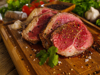 Beef, veal, pork steaks sprinkled with spices on a wooden cutting board. Close-up. Cooking steaks from organic farm meat, restaurant and home cooking recipes. Advertising, banner.
