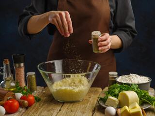 The chef prepares dishes with cheese in a professional kitchen on a wooden table on a dark background. Ingredients for cooking pizza, pasta, spaghetti, lasagna, sauce. Restaurant, hotel, cafe, banner.