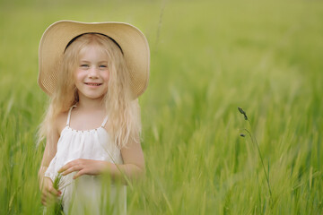 Adorable little girl playing in the wheat field on a warm summer day