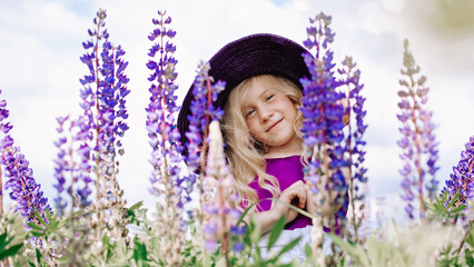 Portrait of a pretty girl in a violet hat with bouquets of lupins in the face