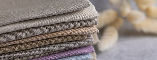 A pile of four folded dull-colored natural linen fabric
