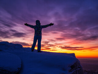 Obraz premium Silhouette of a man with hands raised in the beautiful sunset.