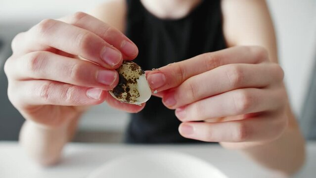 A young girl peels quail eggs from the shell