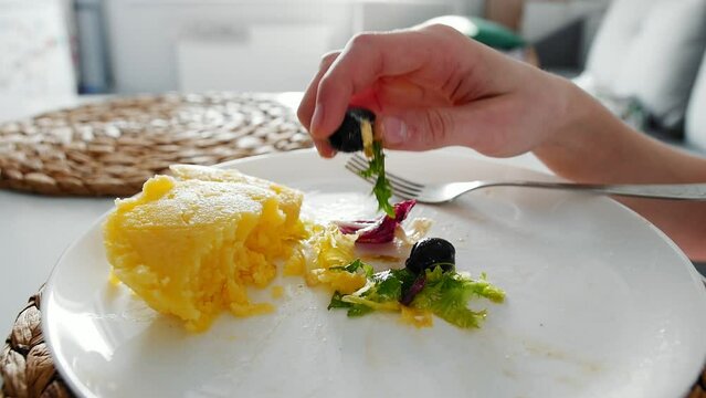 A girl eats vegetable salad with a fork from a white plate