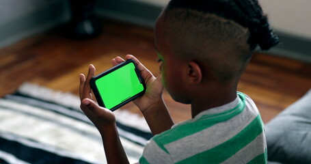 Small boy watching content on phone. Green screen mock-up. African child holding smartphone - Powered by Adobe