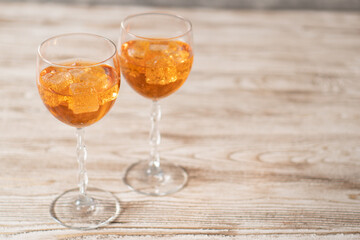 Homemade Aperol spritz. Orange sparkling cocktail in a glass on a wooden table. Copy space on the right