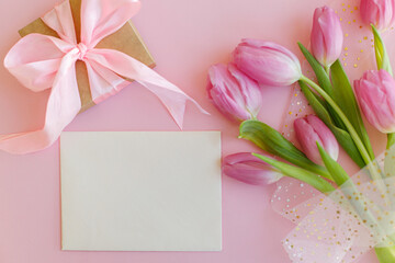 Happy Mothers day. Empty greeting card, pink tulips bouquet and gift box flat lay on pink background. Greeting card template with space for text. Happy womens day. 8 march